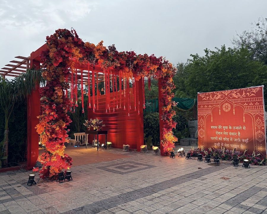 A square gate wrapped in red and orange marigold garlands, at dusk.
